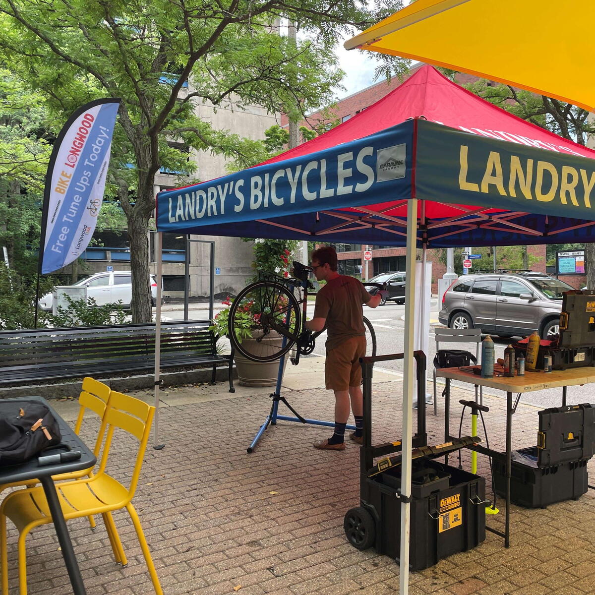 photo of landry's bicycles tent and a worker tuning up a bike