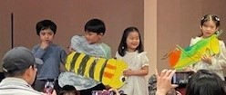 photo of preschoolers at graduation holding artwork